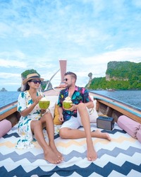 Luxury Longtail boat in Krabi Thailand, couple man, and woman on a trip at the tropical island 4 Island trip in Krabi Thailand. Asian woman and European man mid age on vacation in Thailand. 