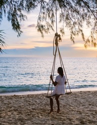 Tropical Island Koh Kood A tropical beach paradise with a beach swing. Women relax on a swing under a coconut palm tree at a beautiful tropical beach White sand holiday summer vacation