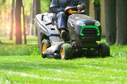 Professional lawn mower with worker cutting the grass in a garden