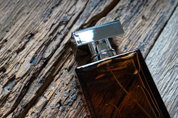 Men's perfume bottle on a weathered wooden background. Eau de toilette with a woody scent concept.