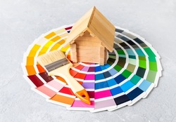 Painting the house or house renovation concept with little wooden house and brush on the color palette catalog.