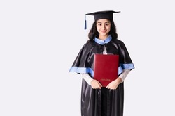 University graduate wearing academic regalia with red diploma. Background with copy space.
