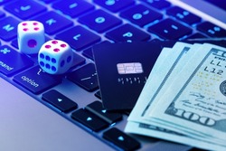 Online gambling background. Making profit with online casino, online gaming concept. Game dice, credit card and dollars lie on a modern laptop keypad close-up.