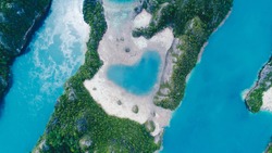 Aerial top view of Love Lagoon Karwapop with turquoise water in heart shape inside of rocky tropical island on Raja Ampat, Papua, Indonesia.