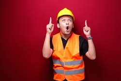 Shock Young asian man worker is surprised and shouting wow with pointing above with his hand isolated on red background.