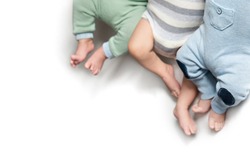 three pairs of legs of newborn babies triplets. twins brothers. Isolate. Copy space 