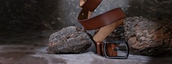 leather belt on a dark background with bark and natural stone on the background. levitation. stylish details of men's clothing.