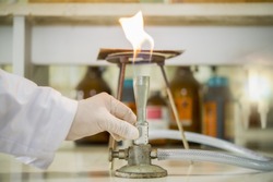 Scientists are adjusting the air to the bunsen burner to provide more complete combustion in the chemical laboratory.