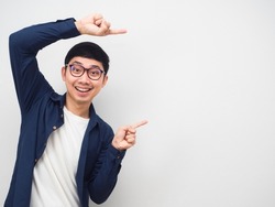 Young man wearing glasses gesture point finger at copy space portrait white background