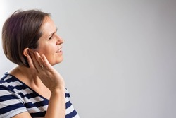 Tinnitus. Closeup up side profile sick female having ear pain touching her painful head. Unhappy woman having ear pain touching his painful head indoor.