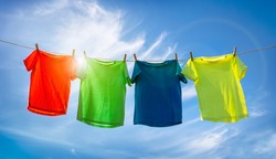 T-shirts hanging on a clothesline in front of blue sky and sun