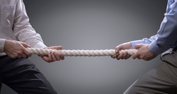 Two businessmen pulling tug of war with a rope concept for business competition, rivalry, challenge or dispute
