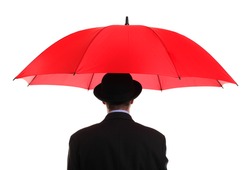 Businessman or insurance agent wearing a bowler hat holding a red umbrella concept for ample insurance cover and business protection