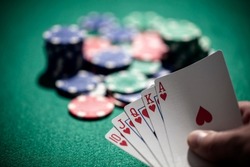 Playing poker in a casino holding winning royal flush hand of cards concept for gambling, betting and winning