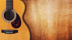 Acoustic guitar resting against a blank grunge background with copy space