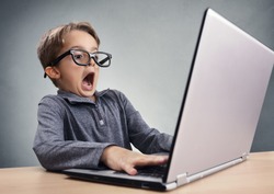 Shocked and surprised boy on the internet with laptop computer concept for amazement, astonishment, making a mistake, stunned and speechless or seeing something he shouldnt see
