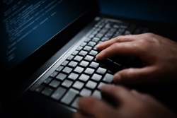 Programmer or computer hacker typing code on laptop keyboard