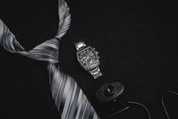 Accessories for businessmen on a dark background. An important meeting of businessmen. A tie with a watch and a webcam. Accessory for connecting to the conference