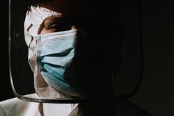 Female hero doctor with mask and face shield crying tear due to coronavirus covid-19 situation 