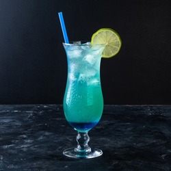 Blue Hawaiian Lagoon Cocktail with with malibu rum, blue curacao, vodka, tequila, pineapple juice, lime juice on a dark background