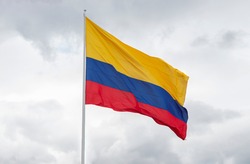Big colombian flag waving with the wind at gey cloudy sky at background