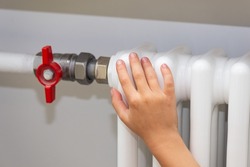 A child's hand is heated on a heating radiator. Economic crisis, saving money, high price.