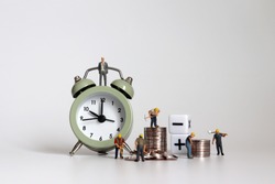 The concept of working hours and wage calculations. Miniature working people with piles of coins.