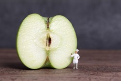 A cut apple and miniature people. Business concept with half an apple and miniature people.