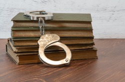 selective focus on handcuffs and a stack of books on a wood table for the concept of literary freedom