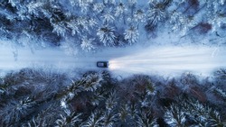Aerial view of night winter road and car in forest. Drone shot.	