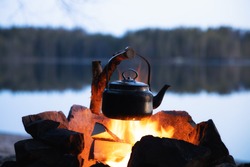 Vintage coffee pot on camping fire. Wonderful evening atmospheric background of campfire. Romantic warm place with fire. The concept of adventure, travel, tourism and camping.