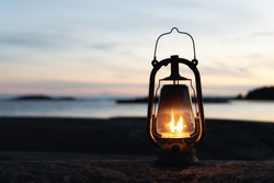 Vintage lantern at sunset, romantic evening at the beach. Mystical scene with old kerosene lamp. Copy space.

