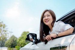 Beautiful Asian woman smiling and looking at the sky in a white car. 