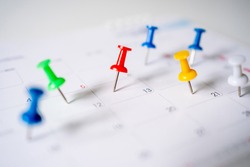 Push pins on calendar, mark the Event day with a red pin. Close-up of red pins.
