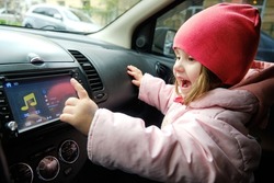 A little girl Changing Radio Station While Listening Music In Car. Listening to the radio in the car. Auto music