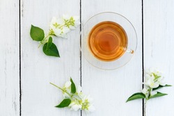 Jasmine tea in glass cup and flowers on a wooden white background ,view from above. Cup with green jasmin tea. Tea time