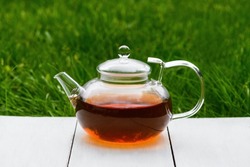 Tea in a glass teapot on a green background. Teapot with green or black tea. Tea time