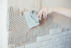 Close-up of ceramic tiles with glue on the wall, worker applies tile adhesive to the wall,
make repairs in the apartment 