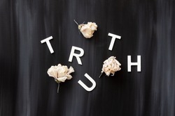 The word, TRUTH, spelled in mixed up capital letters with dried flowers; the word, TRUTH, placed on a black and white painterly background with room for text