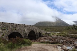 Castle old stone ruins with bridge on the lake Eilean Donan highlander green grass blue sky