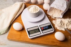 Flour on digital scale with cookie ingredients for baking on wooden table