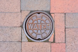 Water meter cover surrounded by square bricks