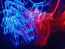 Blue and red light painting photography, long exposure fairy blue and red lights curves and waves against a black background. Long exposure light painting photography. Abstract pink purple swirls
