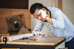 Carpenter working on woodworking machines in carpentry shop, male carpenter cutting wood with circular power saw on workbench