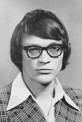 Portrait of young Soviet guy with glasses, in checkered jacket. Vintage black and white paper photo, 1970s. Transferred property, family archive. Outdated quality.