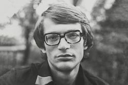 Portrait of young Soviet man with glasses. Vintage black and white paper photo, 1970s. Transferred property, family archive. Outdated quality.