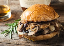 Burger with mushrooms, fried onions and cheese on rustic background