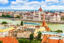 Panoramic view of the Danube river, hungarian parliament building, the Reformed Church and Pest from the opposite side (Buda). Sunny day, green water, cruise boats