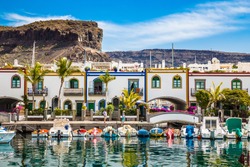 Traditional Colorful Buildings With Boats In Front And Mountain In The Background - Puerto de Mogan, Gran Canaria, Canary Islands, Spain