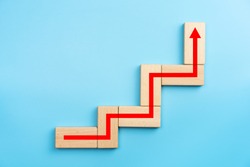 Wooden blocks stacking as step stair with red arrow up, blue background, Business growth success process concept, copy space